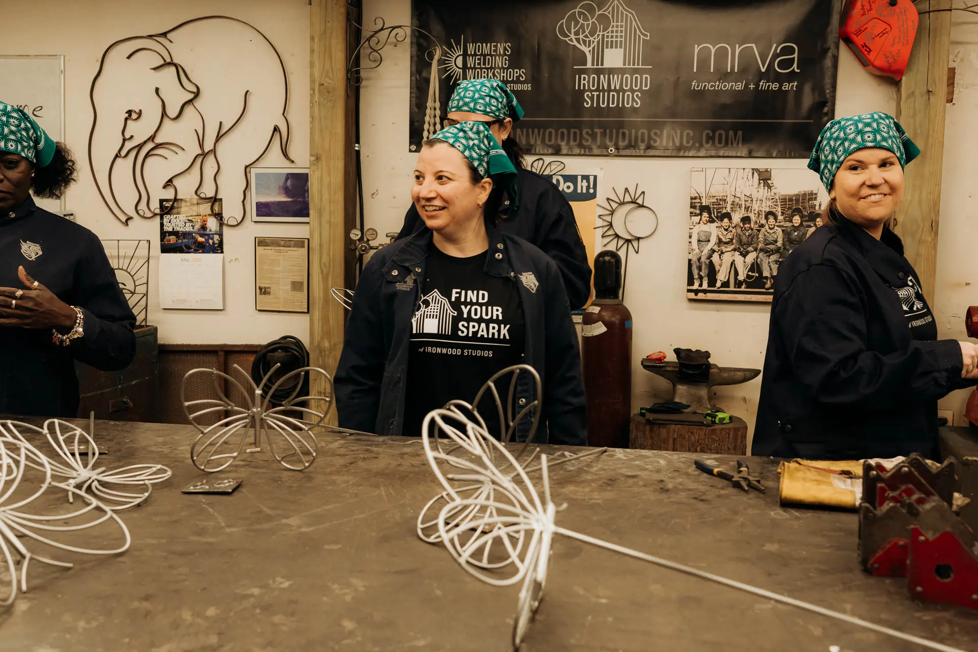 Smiling participants with their finished wire butterfly sculptures on the table