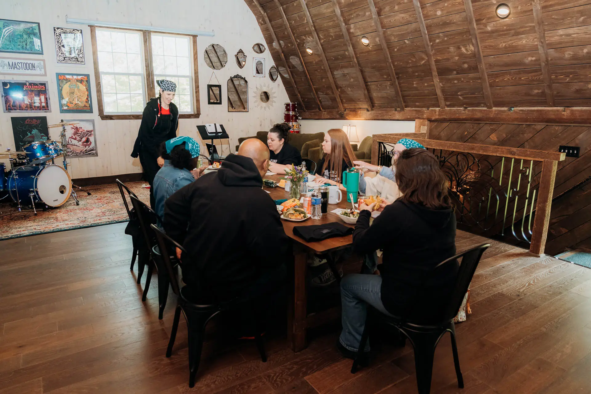 The full team sharing a catered meal at the long table in the loft