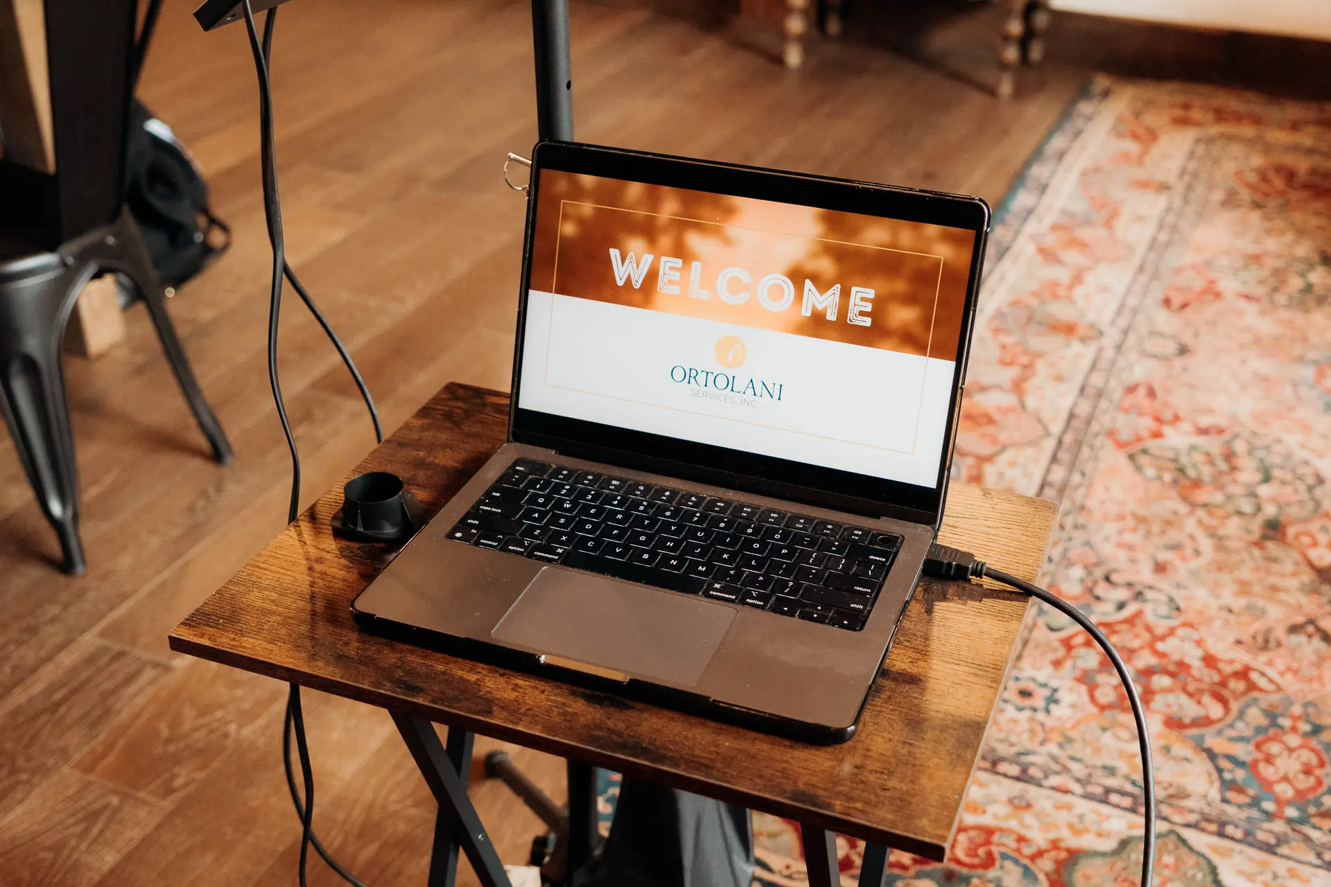 Laptop displaying a welcome presentation slide on a stand in the barn meeting space